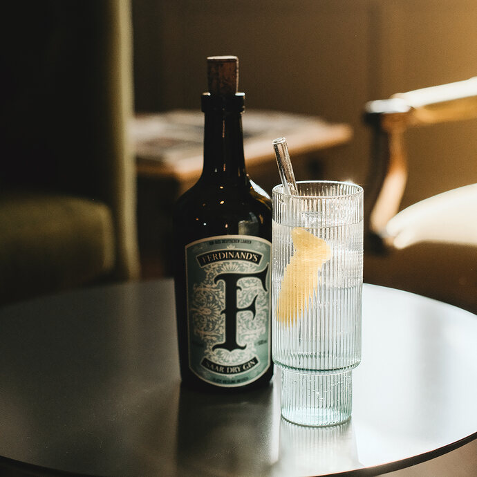 Gin & Tonic mit Ferdinand's Saar Dry Gin in einem hohen Glas auf Salontischchen.